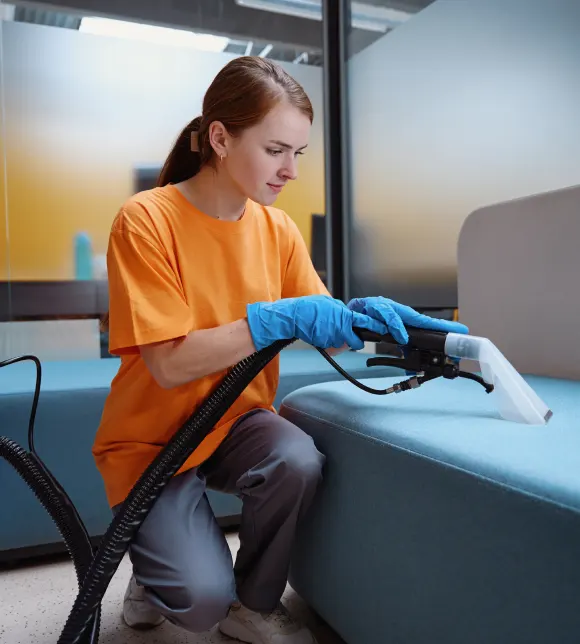 A Choice Cleaning Plus cleaner deep cleaning an apartment sofa with a vacuum