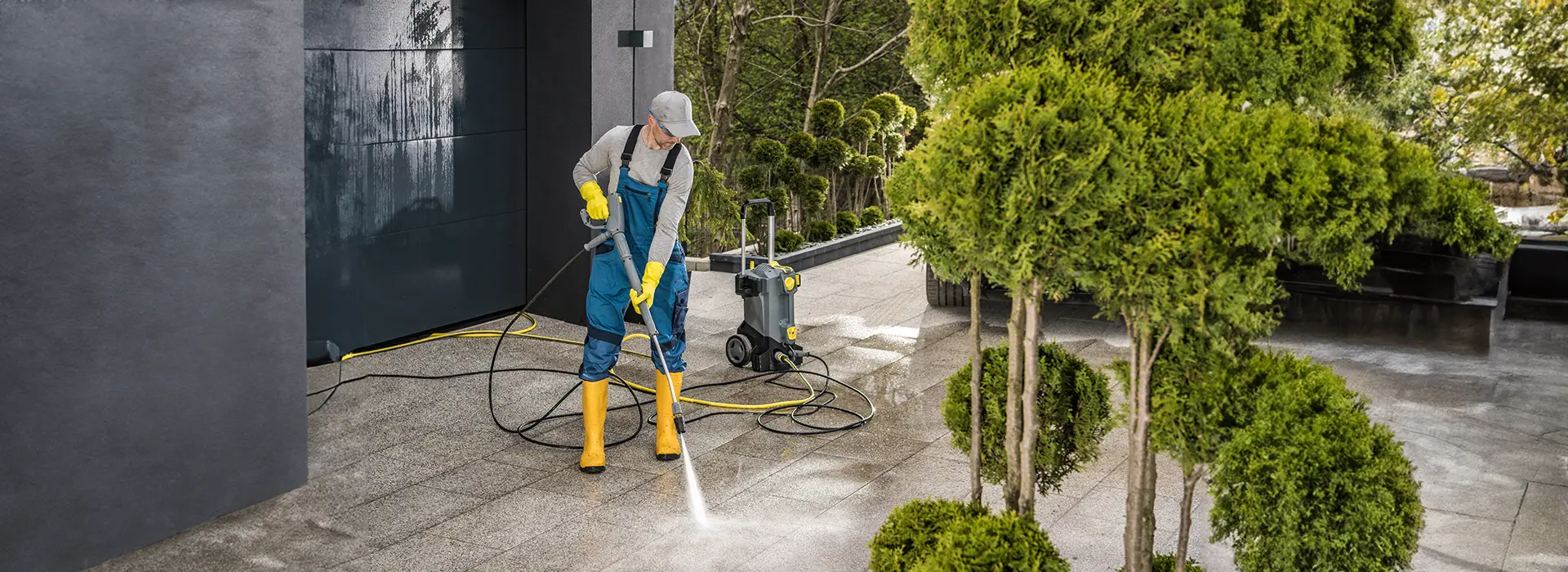 A Choice Cleaning Plus technician pressure washing a residential concrete driveway