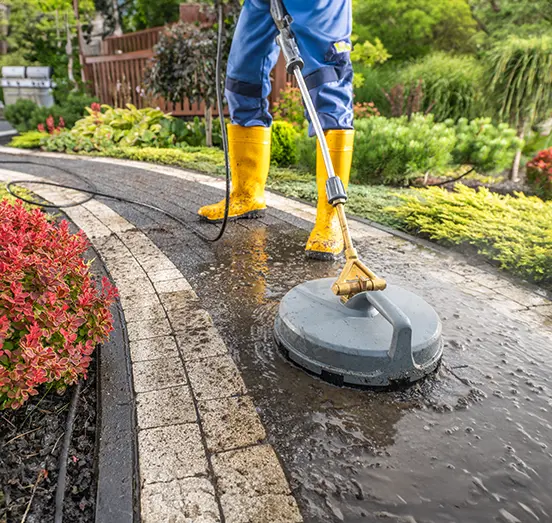 A technician using a surface cleaner attachment on a residential concrete patio
