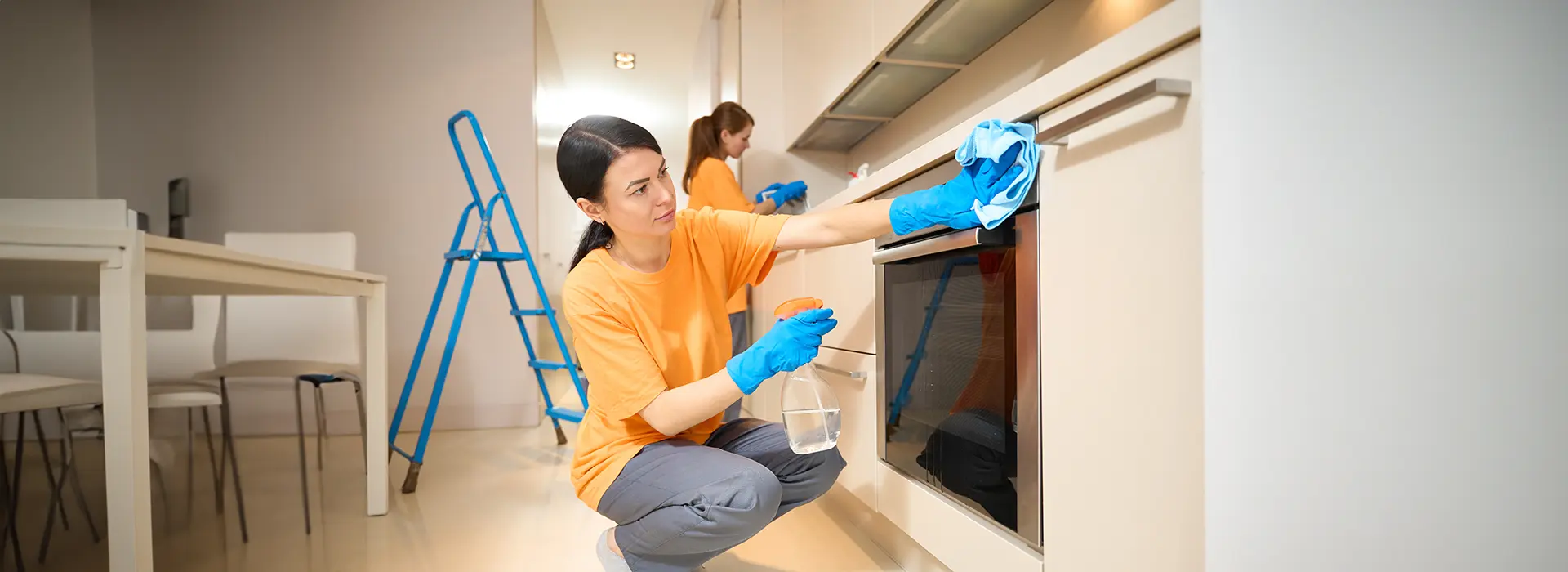 A Choice Cleaning Plus cleaner spraying and wiping down a kitchen oven during a same-day clean