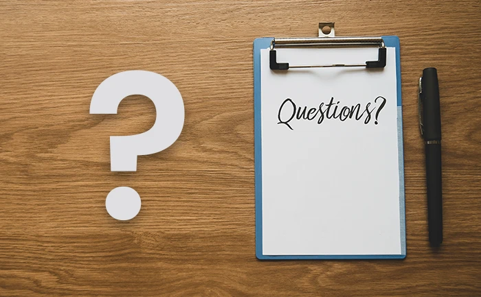 A clipboard reading Questions next to a pen