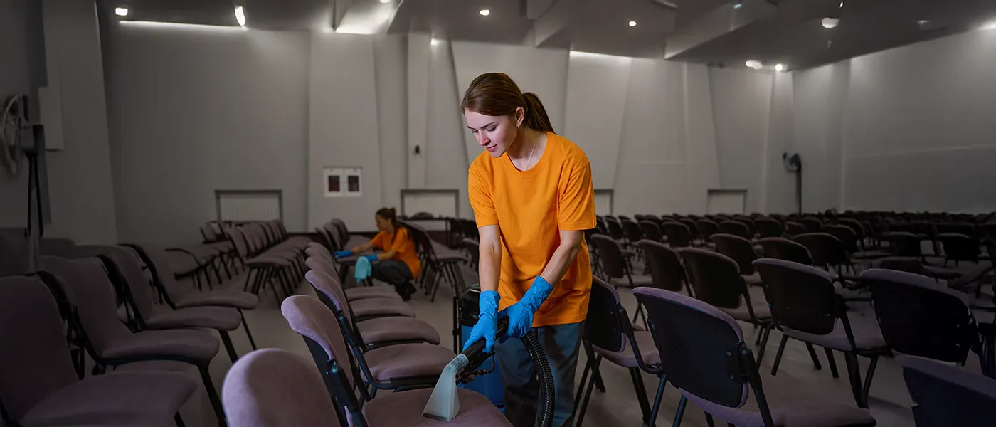 A Choice Cleaning Plus cleaner steam cleaning seating in a dim auditorium at night