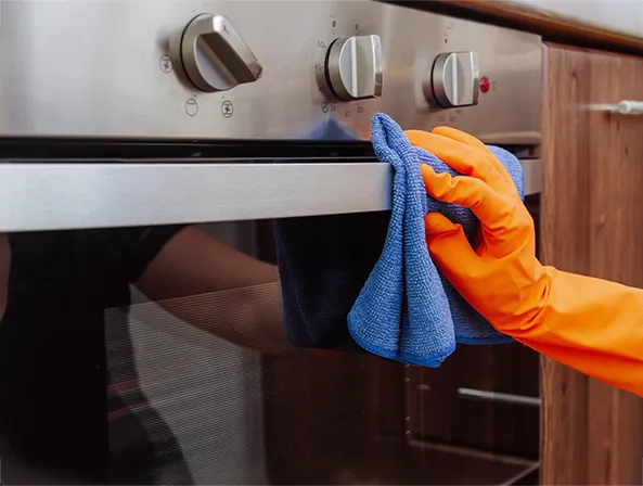A Choice Cleaning Plus technician wiping down stainless steel counters in a commercial kitchen