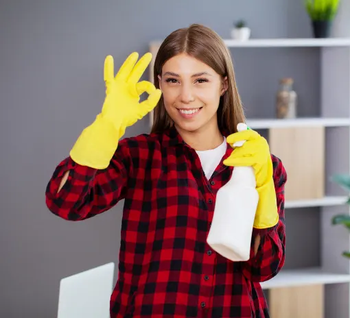 A friendly Choice Cleaning Plus cleaner holding a spray bottle and giving an OK gesture