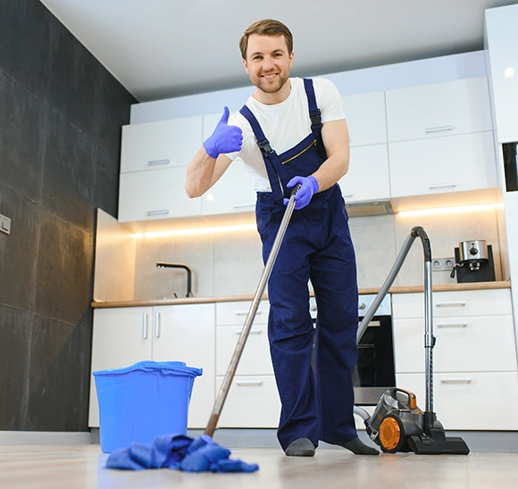 A professional cleaner in blue uniform mopping a student housing kitchen floor